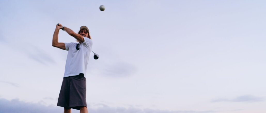 A man swinging a golf club on a scenic outdoor course during the evening.