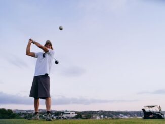 A man swinging a golf club on a scenic outdoor course during the evening.