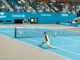Dynamic scene of players in action at the US Open on a bright tennis court.