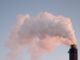 From below of clouds of smoke from industrial factory pipes polluting atmosphere against cloudless sky