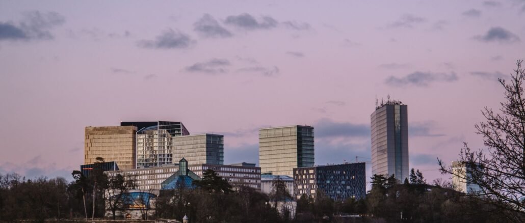 Luxembourg City skyline featuring modern skyscrapers under a soft pink sunset sky.