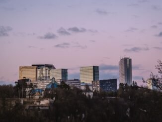 Luxembourg City skyline featuring modern skyscrapers under a soft pink sunset sky.