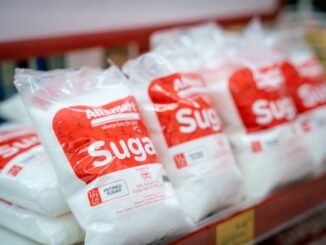 Close-up of sugar bags on a grocery store shelf, highlighting product packaging.
