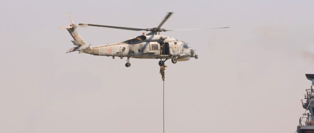 A military helicopter conducting a naval exercise with soldiers rappelling down.