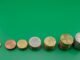 Various euro coins stacked incrementally on a vibrant green background.