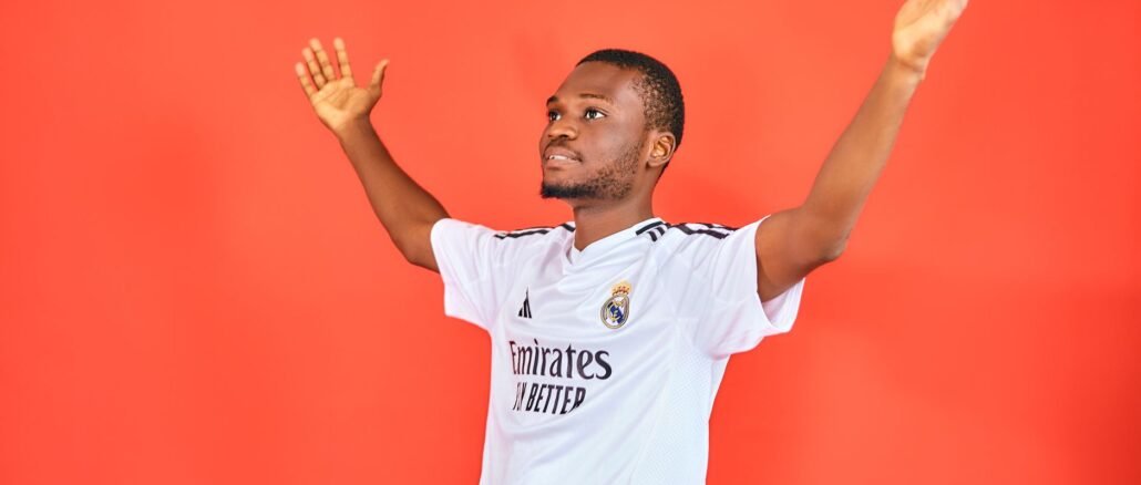 An enthusiastic football fan celebrating with arms raised in a jersey against a red background.