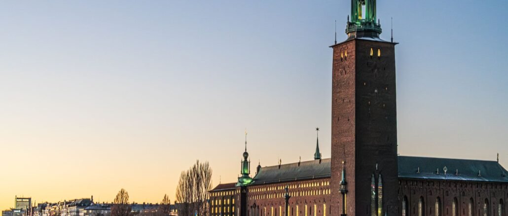 Beautiful view of Stockholm City Hall reflecting on the water during sunset, showcasing its iconic architecture.
