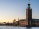 Beautiful view of Stockholm City Hall reflecting on the water during sunset, showcasing its iconic architecture.