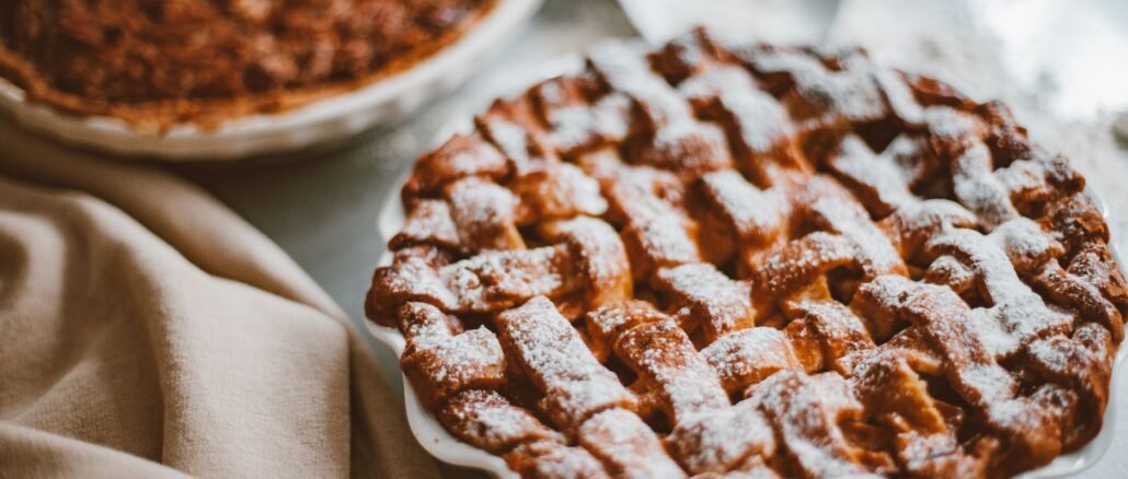 Freshly baked apple pie with lattice crust dusted with icing sugar, perfect for dessert.