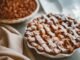 Freshly baked apple pie with lattice crust dusted with icing sugar, perfect for dessert.