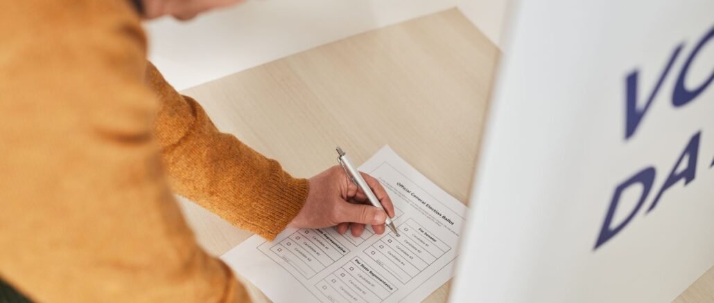 Senior man marking a ballot at a voting booth in an indoor polling station.