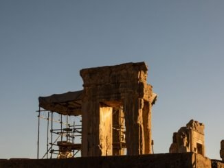 Ancient ruins of Persepolis, Iran, captured during a dramatic sunset, showcasing the architectural remnants and scaffolding.