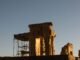 Ancient ruins of Persepolis, Iran, captured during a dramatic sunset, showcasing the architectural remnants and scaffolding.