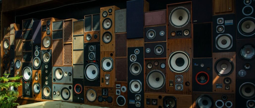 A cozy living room with a striking wall of vintage speakers, showcasing retro audio aesthetics and comfortable seating.