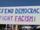 Protest sign reading 'Defend Democracy, Fight Fascism' at an outdoor rally in Elk Grove, CA.