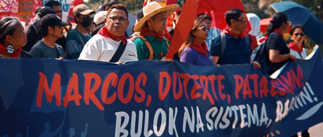 A group of protesters holding a banner during a daytime demonstration outdoors.