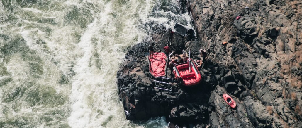 Adventure scene of red rafting gear on rocky riverside, from above.