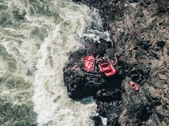 Adventure scene of red rafting gear on rocky riverside, from above.