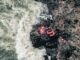 Adventure scene of red rafting gear on rocky riverside, from above.