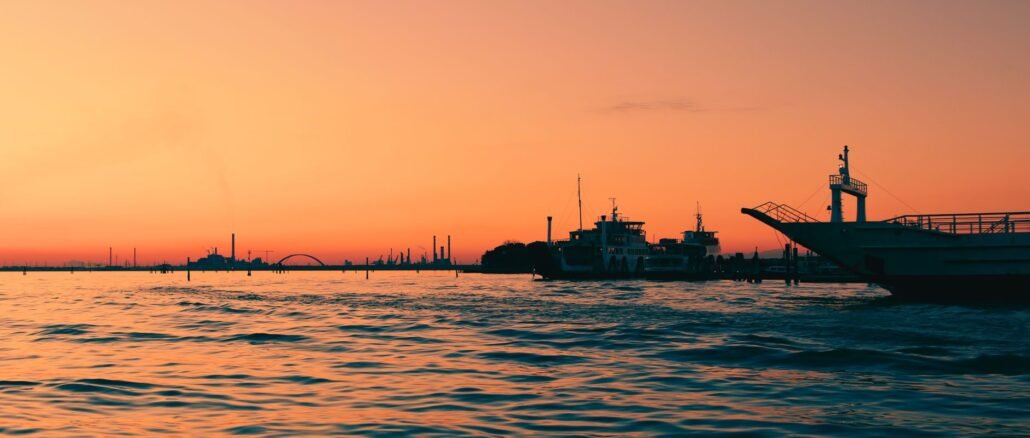 Capture the enchanting Venice sunset, reflecting over calm waters with moored boats.