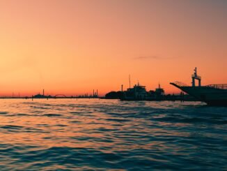 Capture the enchanting Venice sunset, reflecting over calm waters with moored boats.