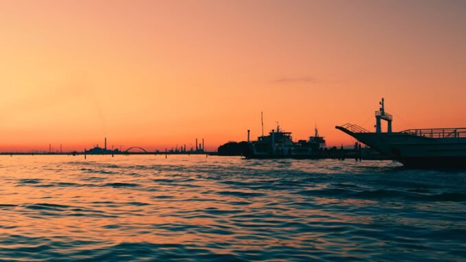 Capture the enchanting Venice sunset, reflecting over calm waters with moored boats.